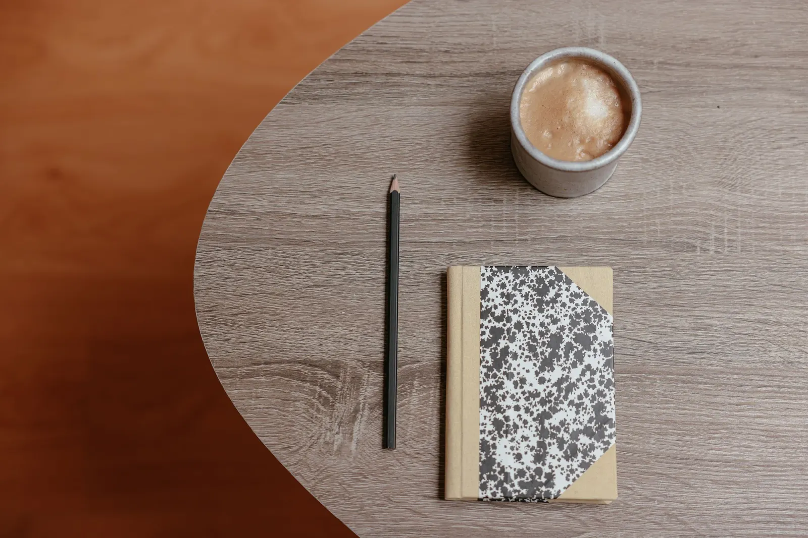 Holztisch mit Kaffee, Notizbuch und Stift
